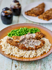 Chicken fried steak with sausage gravy on a brown plate
