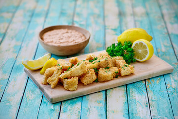 fried catfish bites served on a cutting board with fresh lemon and parsley