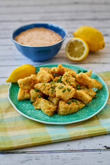 fried catfish bites served on a green plate with fresh lemon and parsley