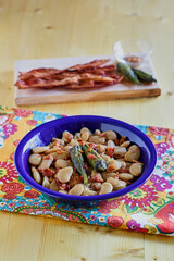 Simmered butter beans with bacon in a blue bowl