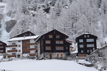 Naklejka premium Snowy cabins in the mountains; Snow-covered chalets in Swiss Alps; Switzerland at wintertime in the mountains