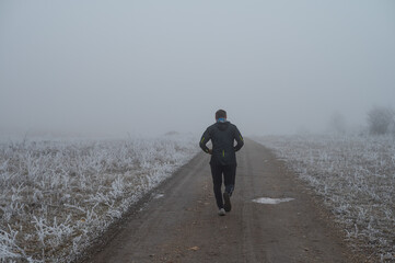 trail runner man running in misty country road
