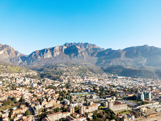 Naklejka premium Aerial view of Lecco city in Lombardy, Italy, with Resegone mountain in the background under clear blue sky
