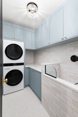 A laundry room with blue cabinets, white washer and dryer, circular tile flooring, subway tile...