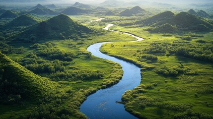 Serene river winding through vibrant green hills in a tranquil landscape during daytime © olegganko