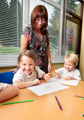 Elementary School: A Cheeky Smile. A cheeky smile on the face of a young primary school girl with her encouraging teacher in the classroom.