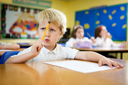 Elementary School: Lost in thought. A thoughtful expression on the face of a young primary school pupil trying to work out a math problem at his desk in class.