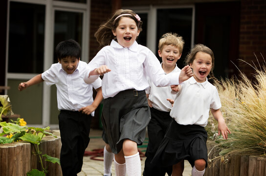 Elementary School: Playtime. A small group of excited primary age pupils running out of school at the end of the day.