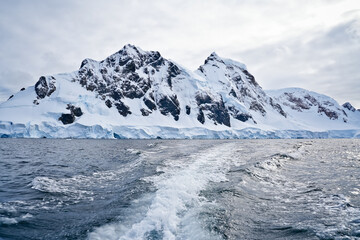 View of ice-covered rocky mountains in Antarctica from a moving boat
