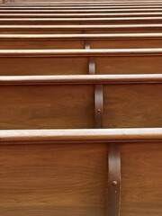 Rows of empty wooden church pews from behind background