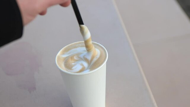 stirring a warm cappuccino with fluffy foam