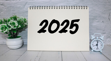 A workspace featuring a notepad with 2025 happy new year. Notebook on the table with the year 2025...