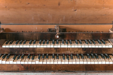 A vintage wooden keyboard displays worn ivory keys, hinting at years of musical creativity. Sunlight filters through, casting a warm glow in a nostalgic, rustic atmosphere
