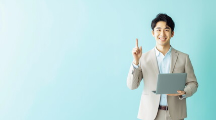 パソコンを片手に人差し指を立てているスーツを着た日本人男性の画像