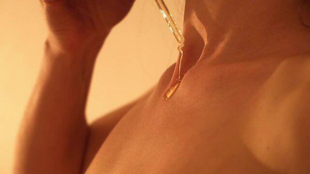 Skin care. Sexy woman dripping aromatic oil on her chest. A drop runs down the girl's body close-up. Using an aphrodisiac. Side view. Youth serum. Love potion. Moisturizing body lotion. Sensitive joy.