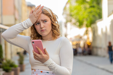 Red hair young woman in long dress use smartphone typing browsing loses becoming surprised sudden...