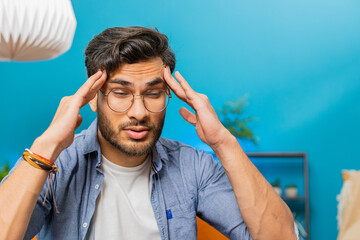 Sick ill Indian man rubbing temples to cure headache problem, suffering from tension and migraine,...