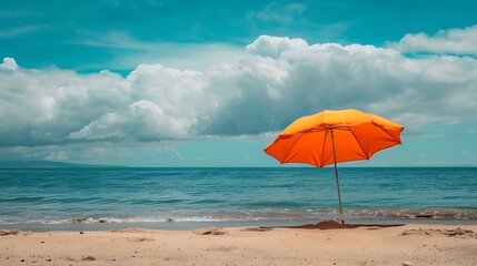 Orange umbrella on the beach with blue sky and white clouds background.