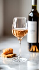 Glass of rose wine with bottle and crackers on marble table