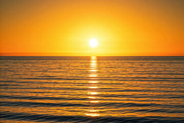 Obraz premium Golden hour sunset illuminating ocean waves crashing on sandy sea beach with colorful cloud sky