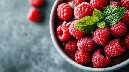 A stunning bowl filled with fresh, vibrant raspberries topped with mint leaves, showcasing a beautiful and healthy dessert option that's perfect for any occasion.