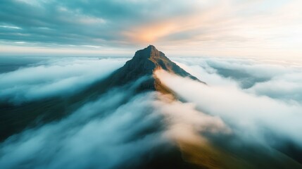 A mystical mountain peak emerges from a blanket of soft clouds, creating a captivating view that inspires wonder and tranquility in nature’s serene beauty.