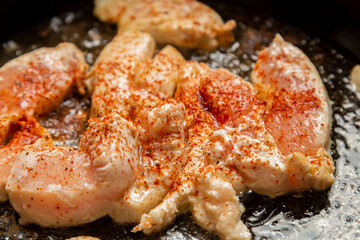chicken fillet fried in spices and oil in a frying pan. horizontal