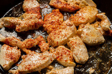 chicken fillet fried in spices crispy crust in a frying pan