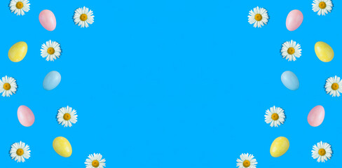 Colored easter eggs and white chamomile on the blue background. Copy space. Top view. Flat lay.