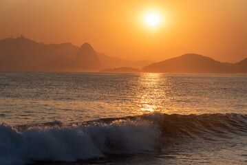 Fototapeta premium Por do sol laranja refletindo no mar com a silhueta do Rio de Janeiro