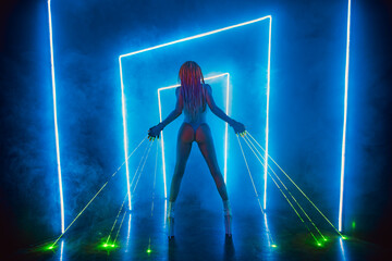 Young woman dancer posing in dark night club interior with green lasers