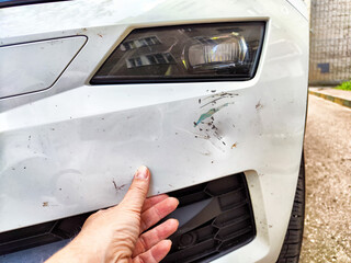 A person is currently pointing at a damaged car bumper in front of them
