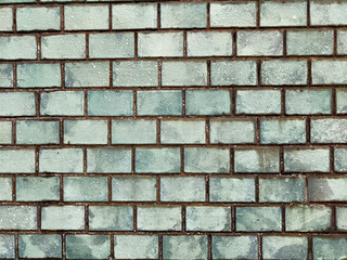 Textured wall featuring blue and green bricks provides a unique background suitable for various design applications