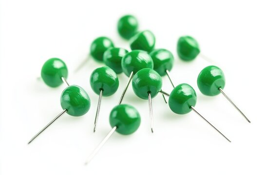 A cluster of green pins sits atop a white surface, awaiting use or organization