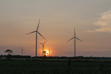 wind turbines stand majestically against a twilight sky, generating renewable energy amidst lush green fields