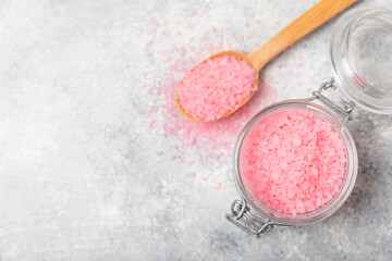 Sea salt for bath with aroma and rose flowers on textured wooden background. Pink sea salt. Spa treatments. Natural salt with herbs and essential oils. skincare concept. Meso for text. Copy space