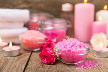 Sea salt for bath with aroma and rose flowers on textured wooden background. Pink sea salt. Spa treatments. Natural salt with herbs and essential oils. skincare concept. Meso for text. Copy space