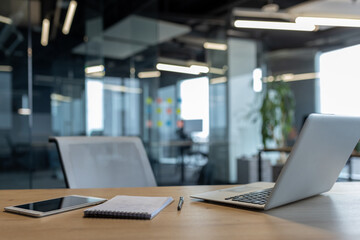 Contemporary workspace featuring a laptop, a smartphone, and a notebook on a wooden table. The...