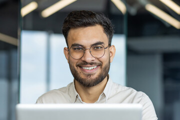 Latin american businessman smiles at the camera, exuding success and positivity while working.