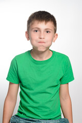 A portrait of a boy with short brown hair, wearing a bright green t-shirt. He's making a funny face, puffing out his cheeks. The image is simple and clean, shot against a plain white background.