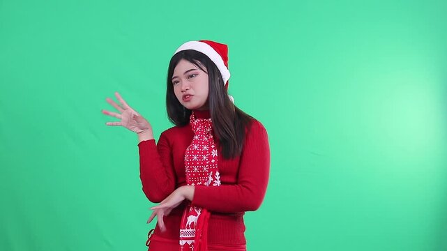adult woman wearing Christmas sweater, Santa hat and scarf, showing talkative expression while making continuous talking gestures on green background,green screen