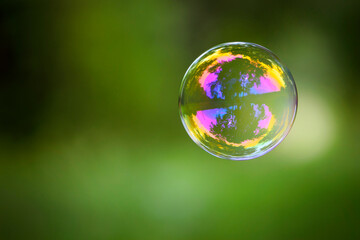 multicolored soap bubble on a green background. Soap bubble. Isolated on green, in spring or...
