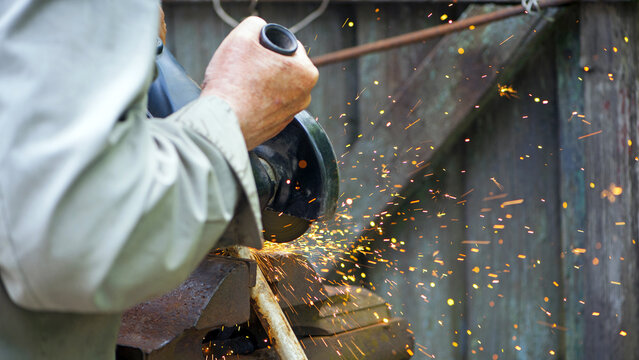 Heavy industry worker cutting steel with angle grinder. Cutting an old rusty pipe. dismantling. close-up. old pipe and work with grinder. hands of a master, professional. sparks of hot metal fly