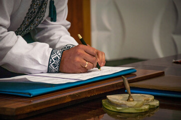 A man in a national Ukrainian costume signs the marriage registration book.
