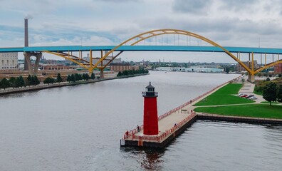 Aerial view of the iconic red lighthouse, a pedestrian walkway, and the city skyline with a bridge. People enjoy the waterfront. Milwaukee Pierhead Lighthouse, Milwaukee, Wisconsin, United States