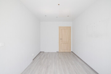 A minimalist empty room features a wooden door along with stylish grey flooring design
