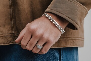 Fototapeta premium Closeup photo of male hand with silver chain bracelet, ring. Man wears casual attire. Stylish accessory. Modern jewelry. Focus on wristband. Hand crafted details visible. Trendy accessory. Young