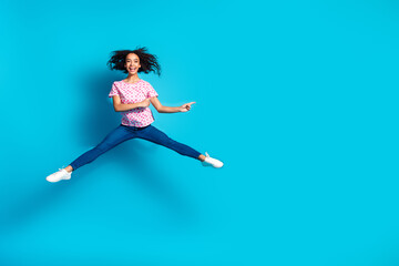 Full length photo of cheerful pretty lady dressed pink t-shirt jumping high pointing empty space isolated blue color background