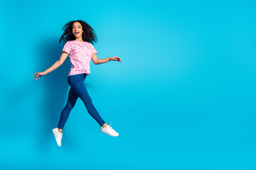 Full length photo of shiny attractive lady dressed pink t-shirt walking jumping high empty space isolated blue color background