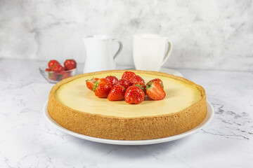 Classic sliced homemade New York cheesecake with fresh strawberries served on a marble countertop. Homemade dessert. 
